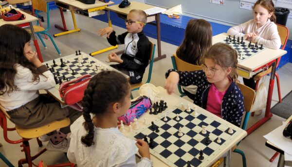 Élèves du primaire devant des plateaux d'échecs